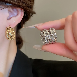 Detail of interlocking link hoop earrings in gold and silver with cubic zirconia stones