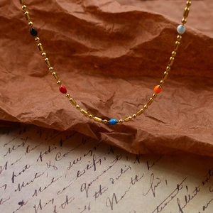 Colorful drip glaze bead necklace with gold plated chain on vintage paper background
