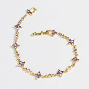 Close-up of gold flower bracelet with purple zirconia and classic fold-over clasp