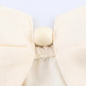 Two-piece resort set in beige cotton linen with close-up of natural wooden button