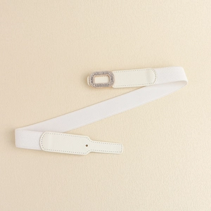 White elastic waist belt with a rectangular rhinestone buckle on a textured background