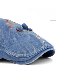 Nahaufnahme der blauen Denim-Baskenmütze mit Blumenmuster und Knopf im Detail