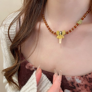 Detail of amber beaded necklace with yellow fairy pendant on model neck