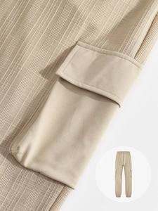 Detail of light khaki cargo pants showing waffle texture fabric and side pocket stitching