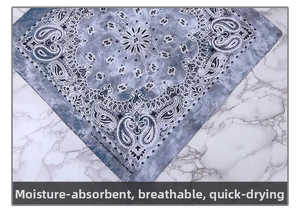 Detail of 100% cotton paisley bandana in grey-blue laid on a marble surface