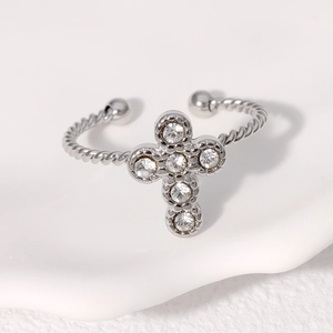 Detail of silver cross open ring featuring zircon stones and rope textured band style