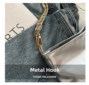 Detail of golden lobster clasp hardware and leather-chain strap on a silver bag