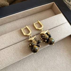 Detailed shot of 18k gold plated bird earrings with tiger eye beads on velvet tray