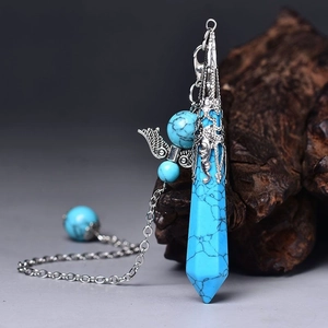 Macro detail of turquoise hexagonal crystal pendant with silver wing chain accessory