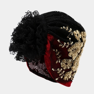 Close-up of turban hat featuring intricate gold floral embroidery and lace flower detail