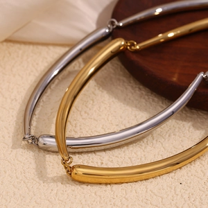 Detail of 18K gold and silver bamboo style necklaces on silk and wooden tray background