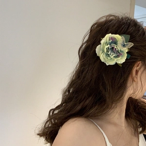 Detail showing fabric flower hair claw with butterfly accent on model's long hair