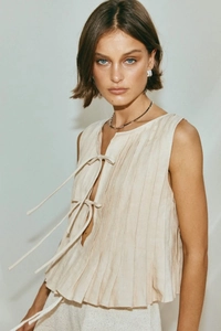 Detailed close-up of beige pleated cotton linen sleeveless top with front tie strings