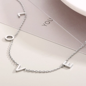 Gros plan du collier avec pendentif LOVE en argent sur une assiette en céramique