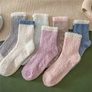 Detail of coral fleece socks showing non-slip silicone grippers on thickened colorful soles