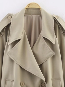 Detailed view of notch lapels, shoulder epaulettes, and buttons on a khaki trench coat