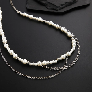 Men's double-layered pearl and silver chain necklace on dark stone display