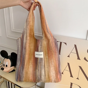 Détail du sac cabas en laine à rayures colorées montrant la texture et l'étiquette