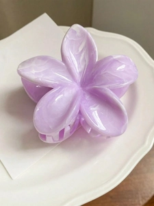Détail de la pince à cheveux fleur lilas avec texture marbrée sur céramique blanche
