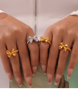 Dettaglio di eleganti anelli a forma di fiocco in oro e argento sulle dita