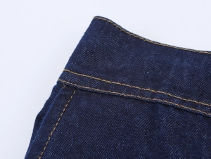 Detailaufnahme der gelben Kontrastnähte auf dunkelblauem Denim-Stoffgewebe