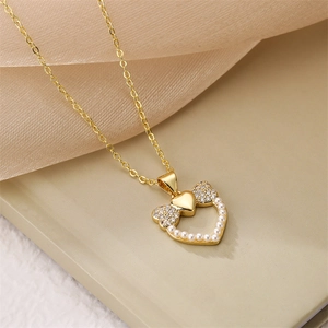 Vue macro d'un collier cœur doré avec perles et zircon sur fond de tissu beige