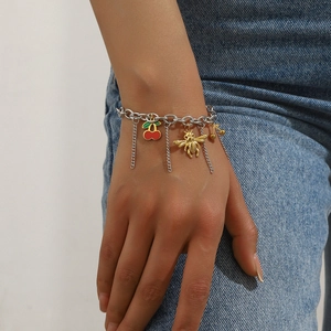 Fashionable charm bracelet with gold bees, red cherries, and tassel chains on a model wrist