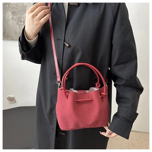 Close-up of red suede tote bag paired with a black coat for a minimalist winter look