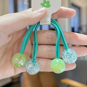 Close-up of cute green and blue glitter ball hair ties with Hand Made label details