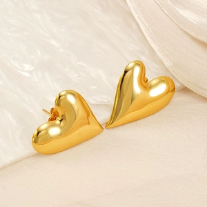 Close-up of golden heart earrings in 18K plated stainless steel on soft fabric