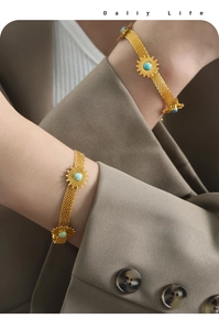 Detail of 18K gold mesh bracelet with turquoise sunburst charm on a female wrist