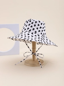Detailed close-up of white sun hat with black heart pattern and matching windproof strap