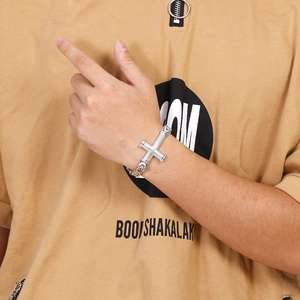 Close-up of a silver hip-hop style cross pendant bracelet on a male model wrist