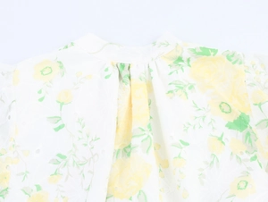 Detailed close-up of white dress with yellow floral print and delicate lace texture