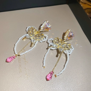 Detail view of heart and butterfly drop earrings with pearl fringe and pink crystals