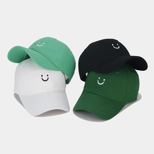 Close-up of four colored cotton baseball caps with minimalist smiley face embroidery detail
