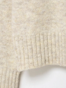 Close-up of oatmeal wool blend knit texture with thick ribbed hem and fluffy yarn finish