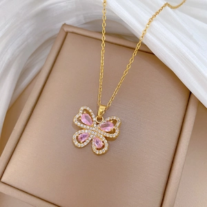 Detailed shot of a gold butterfly necklace with pink crystals on white silk