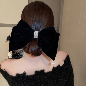 Détail de pince à cheveux en velours noir avec strass et perle suspendue élégante