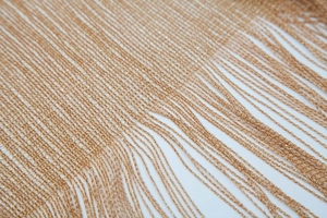 Detailed close-up of fine golden metallic tassels on a lightweight summer shawl wrap