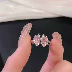 Close-up of silver butterfly ring with pink gemstone wings and sparkling diamond accents