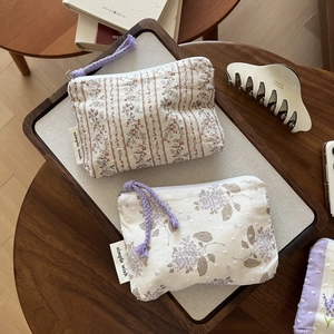 Detail of floral cotton pouches with zipper and purple cord in a cozy wooden tray