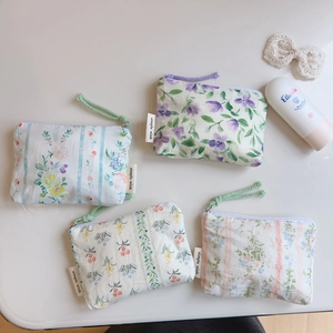 Flat lay of small floral cotton pouches with woven zipper pulls and branding labels