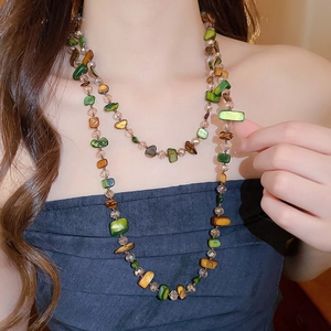 Detail of layered bohemian necklace featuring irregular green and brown natural stones
