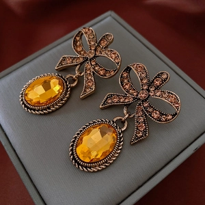Macro detail of vintage bow earrings with amber gems and crystal inlay on leather