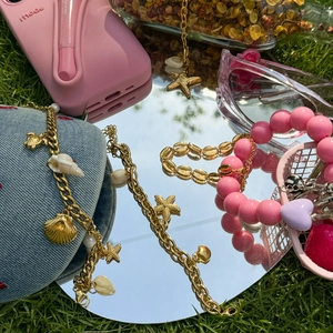 Close-up of ocean-themed jewelry with golden starfish pendants on a mirror surface