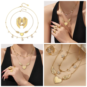 Close-up of golden wing and heart jewelry set including necklace, ring and earrings