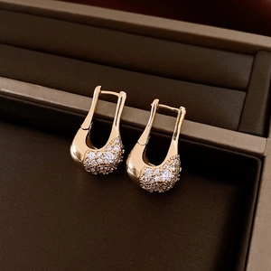 Detailed view of U-shaped gold earrings with pavé zircon stones in a jewelry box