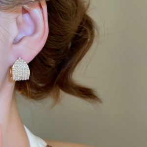 Close-up of elegant gold pearl drop earrings with sparkling rhinestones on model