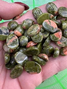 Polished oval unakite cabochon stones showing green and pink textures in close-up